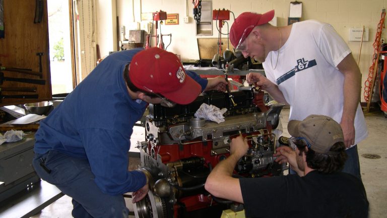 Agricultural engineering students working on a tractor engine.